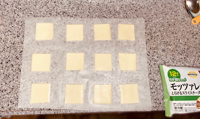 スライスチーズを四等分にし計3枚分のチーズをクッキングシートに並べた状態