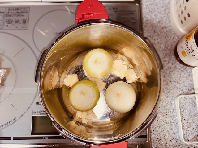 煮込み鍋にニンニク、処理した玉ねぎの切り込みを下にして入れた状態